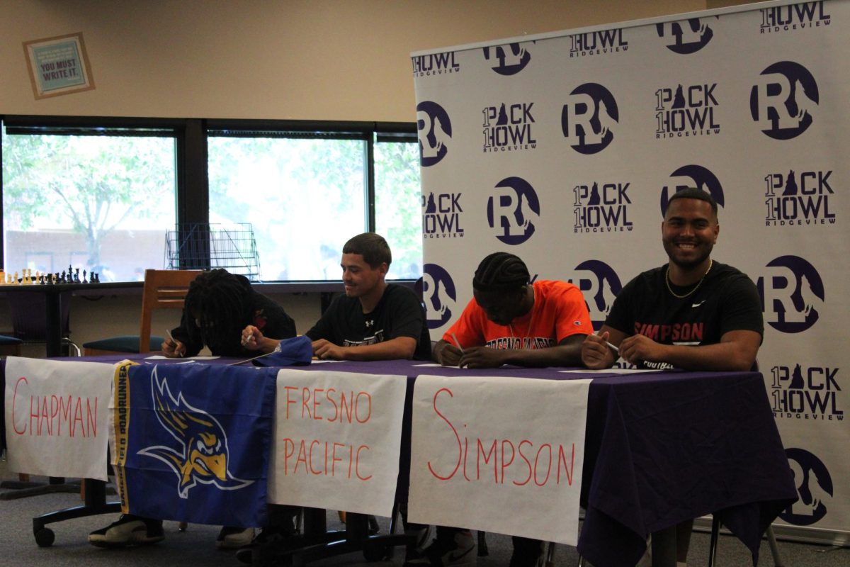 Seniors Jacob Ayala, Jovarie Hayden, Adam Salazar, and Ezekiel Thomas sign in the library to go to college. 