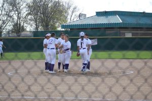 The Softball team talks at the center mound. 